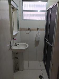 a bathroom with a sink and a shower with a window at Apê Temporada Vila Guilhermina in Praia Grande