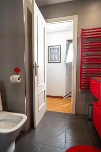 La salle de bains est pourvue de toilettes blanches et d'une porte rouge. dans l'établissement la casa de los lapiceros, à Talavera de la Reina