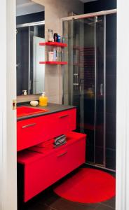 La salle de bains est pourvue de tiroirs rouges et d'une douche en verre. dans l'établissement la casa de los lapiceros, à Talavera de la Reina