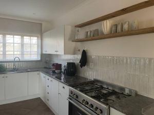 a kitchen with white cabinets and a stove top oven at Cipresso Guesthouse in Tierpoort