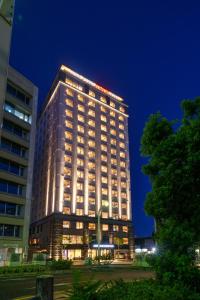 a tall building with lights on it at night at Hotel GrandConsort Naha in Naha