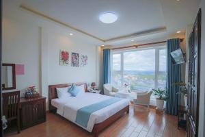 een slaapkamer met een bed en een groot raam bij Rose Valley Hotel Da Lat Vietnam in Da Lat