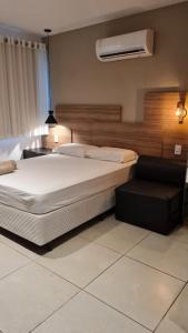 ein Schlafzimmer mit einem großen weißen Bett und einem Stuhl in der Unterkunft FLAT CONFORTÁVEL EM BOA VIAGEM in Recife