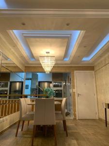 a dining room with a table and a chandelier at Apartamento Novissimo Aquarius II in Poços de Caldas