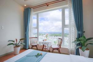 een slaapkamer met een groot raam met een tafel en stoelen bij Rose Valley Hotel Da Lat Vietnam in Da Lat