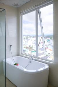 een bad in een badkamer met een groot raam bij Rose Valley Hotel Da Lat Vietnam in Da Lat