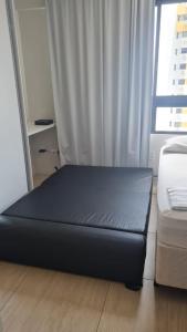 Cama negra en habitación con ventana en FLAT BOA VIAGEM PRÓXIMO A PRAIA, en Recife