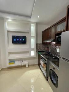 cocina con fogones y TV en la pared en Studio on the ground floor in Sharm Hills Resort with private garden and pool view, en Sharm El Sheikh