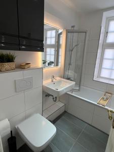 a white bathroom with a sink and a toilet at Lykkefund - Ferienwohnungen in Hafennähe in Glückstadt