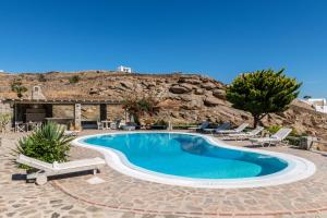 una piscina en un complejo con sillas y una montaña en Yalos Mykonos Ornos Pouli private apartments w shared swimming pool, en Mykonos ciudad