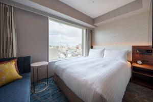 a hotel room with a large bed and a window at Hotel GrandConsort Naha in Naha