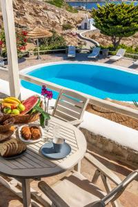 a table with a tray of food next to a swimming pool at Yalos Mykonos Ornos Pouli private apartments w shared swimming pool in Mikonos