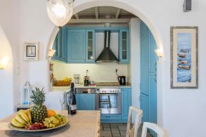 a kitchen with blue cabinets and a bowl of fruit on a table at Yalos Mykonos Ornos Pouli private apartments w shared swimming pool in Mikonos