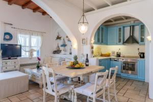 a kitchen with blue cabinets and a table and chairs at Yalos Mykonos Ornos Pouli private apartments w shared swimming pool in Mikonos