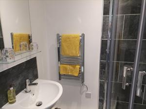 uma casa de banho com um lavatório e um chuveiro com toalhas amarelas em Victorian Renovation Room 8 em Liverpool
