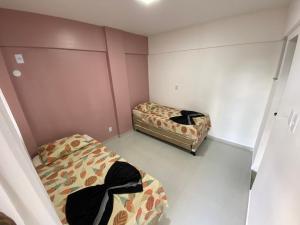 twee bedden in een kleine kamer met roze muren bij Apartamento Cobertura Paraíso das Águas - GUARAJUBA in Camaçari