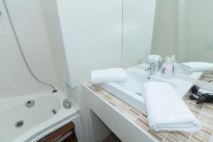 a white bathroom with a sink and a tub at Budapest Bed and Breakfast in Budapest