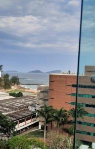 uma vista para um edifício com palmeiras e o oceano em Flat bela vista master em Macaé