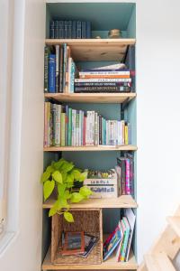 une étagère remplie de livres avec une plante en pot dans l'établissement La maison bohème, au Havre