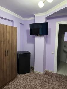 a room with a toilet and a tv on the wall at Hotel international in Yerevan