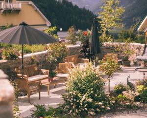 eine Terrasse mit Bänken, einem Sonnenschirm und Blumen in der Unterkunft Nefer, Haus in Bad Gastein