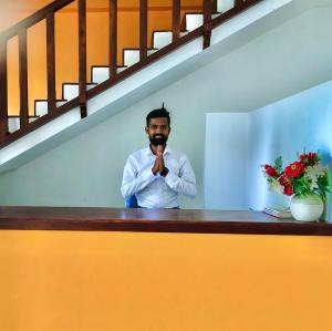 a man standing behind a counter with his hand in his mouth at Sundowners Guesthouse in Hikkaduwa