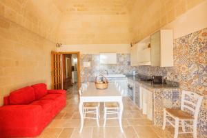 a kitchen with a red couch and a white table at Casolare Lodedo in Ceglie Messapica