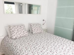a white bedroom with a bed with pillows and a mirror at CENTRO PICACHO in Málaga