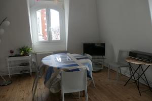 Cette chambre dispose d'une table, de chaises et d'une télévision. dans l'établissement Appartement - Villa Léopold à Malo, à Dunkerque