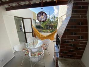 un patio con mesa, sillas y hamaca en Apartamento Cobertura Paraíso das Águas - GUARAJUBA, en Camaçari