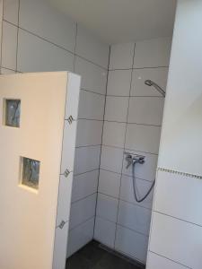 y baño con ducha de azulejos blancos. en Ferienwohnung am Minoritenhof, en Sinzing