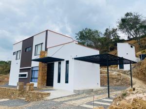 una casa blanca en una colina con dos sombrillas negras en San Gil Villa 48 Palmaire en San Gil