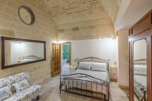 a bedroom with a bed and a mirror and a couch at Casolare Lodedo in Ceglie Messapica