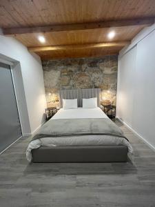 a bedroom with a large bed and a stone wall at Refúgio do Vale in Celorico de Basto +24 photos