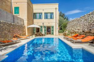 a swimming pool with chairs and a house at Djar Ta Menzja 1 Holiday Home in Sannat