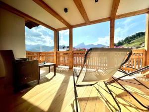 a chair on a deck with a view of the mountains at Ciasa de Zeno in La Valle