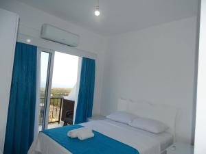 a bedroom with a bed and a large window at Karpaz Sunset Hotel in Rizokarpaso