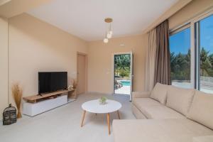 a living room with a couch and a tv and a table at Spartakos Luxury Villa 6 in Planos