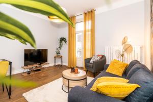 Una sala de estar con un sofá azul y un televisor. en Audace - Magnifique Appartement 75m2 - Position Centrale Gare-Pompidou-Nouvelle Ville - Garage Privé - 2 à 4 Personnes, en Metz