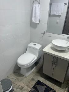 een witte badkamer met een toilet en een wastafel bij Acogedor apartamento en Itagui in Itagüí