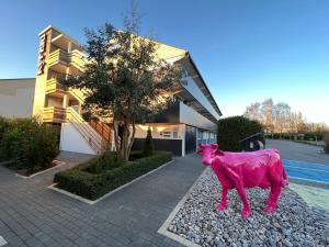 różowy posąg krowy przed budynkiem w obiekcie Kyriad Lisieux w mieście Lisieux