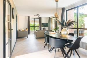 a dining room and living room with a table and chairs at Coco Wellness Bungalow in Ewijk