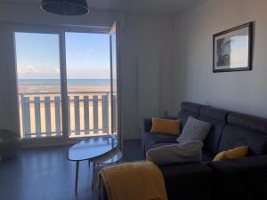ein Wohnzimmer mit einem Sofa und Meerblick in der Unterkunft Appartement sur la plage de Malo les bains vue mer in Dunkerque
