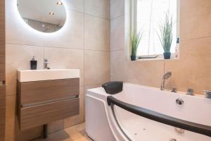 a bathroom with a tub and a sink and a mirror at Coco Wellness Bungalow in Ewijk