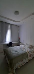 a bedroom with a bed and a chair and a window at Cantinho familiar-Humaitá - somente mulheres - just women in Rio de Janeiro