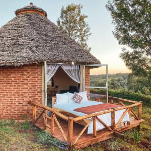 a bed in a brick building with a thatch roof at Foresight Eco Lodge & Safari in Karatu