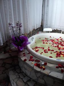 uma casa de banho com uma banheira cheia de flores vermelhas e um arranjo de flores em Pousada Santa Clara em Visconde de Mauá