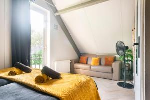 a bedroom with a bed and a couch and a window at Coco Wellness Bungalow in Ewijk