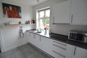 a kitchen with white cabinets and a black counter top at Billesgade Rooms in Odense