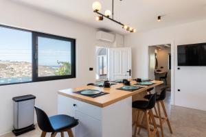 une cuisine avec un îlot doté de chaises et d'un comptoir dans l'établissement Yalos Mykonos 4 Bedroom Luxury house 5 minute from Ornos Beach w sea & Sunset view, à Mykonos